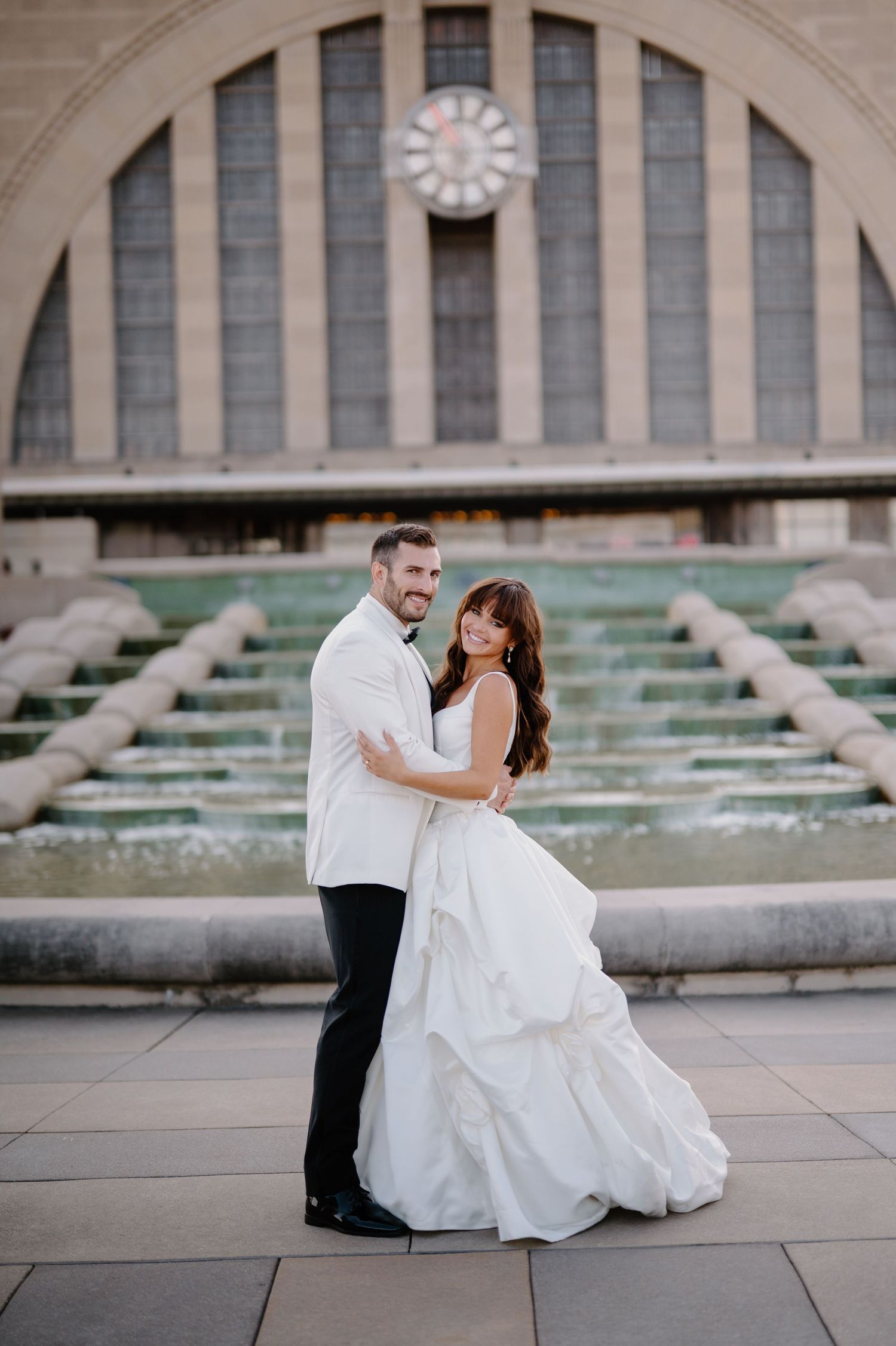 A romantic wedding couple shares intimate moments in front of a grand historic building with stone steps.