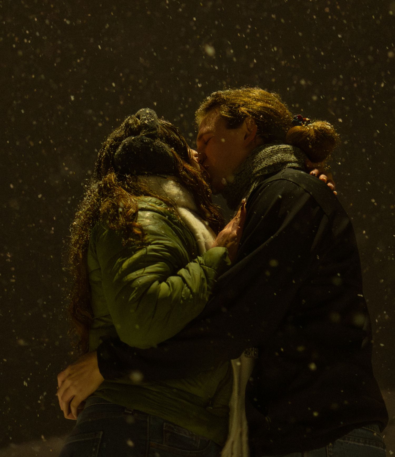 Cinematic snowy couples portrait capturing a romantic kiss beneath a streetlight