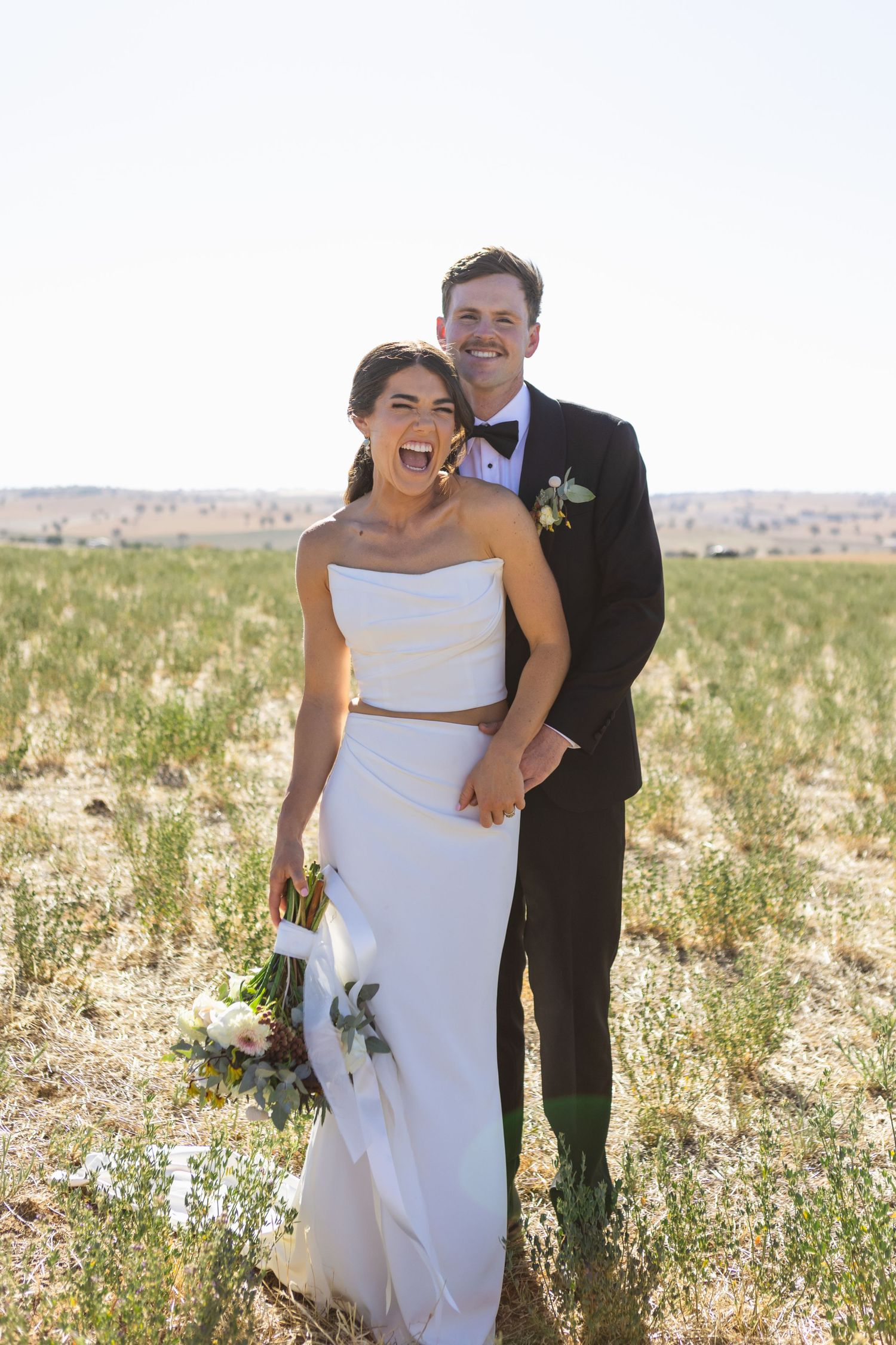 Bride and groom laughing in paddock at NSW Country wedding