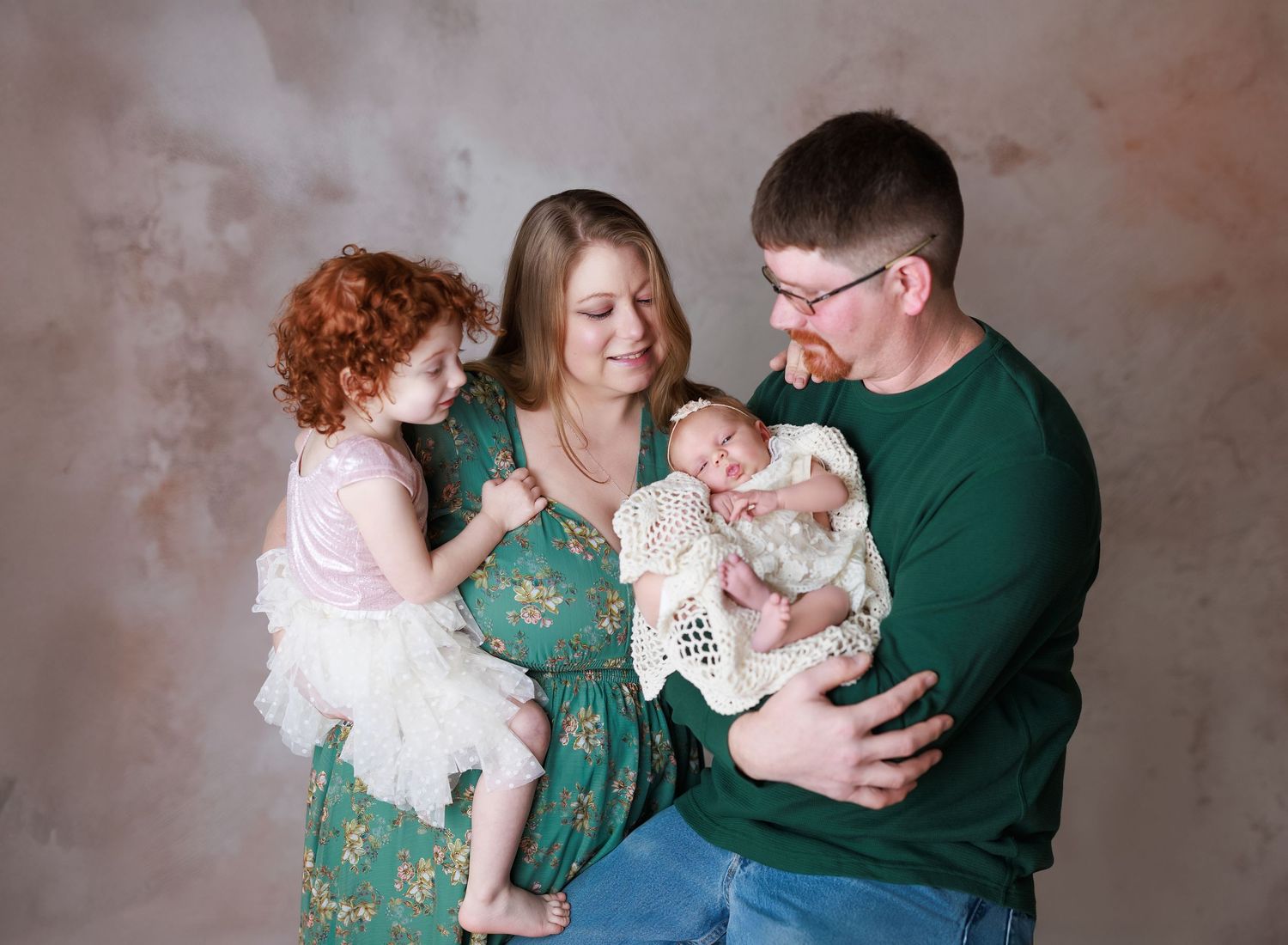 A series of candid family moments with a newborn baby captured in a studio against a textured tan backdrop.