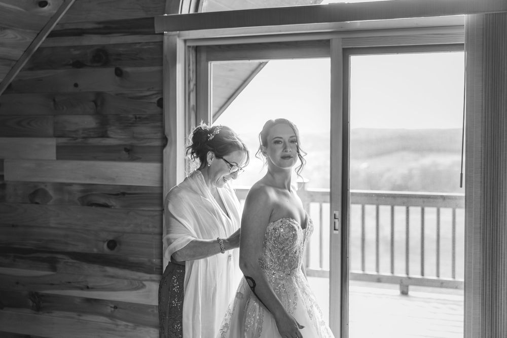 Black and white photos showing candid moments of wedding preparation in a rustic cabin interior.
