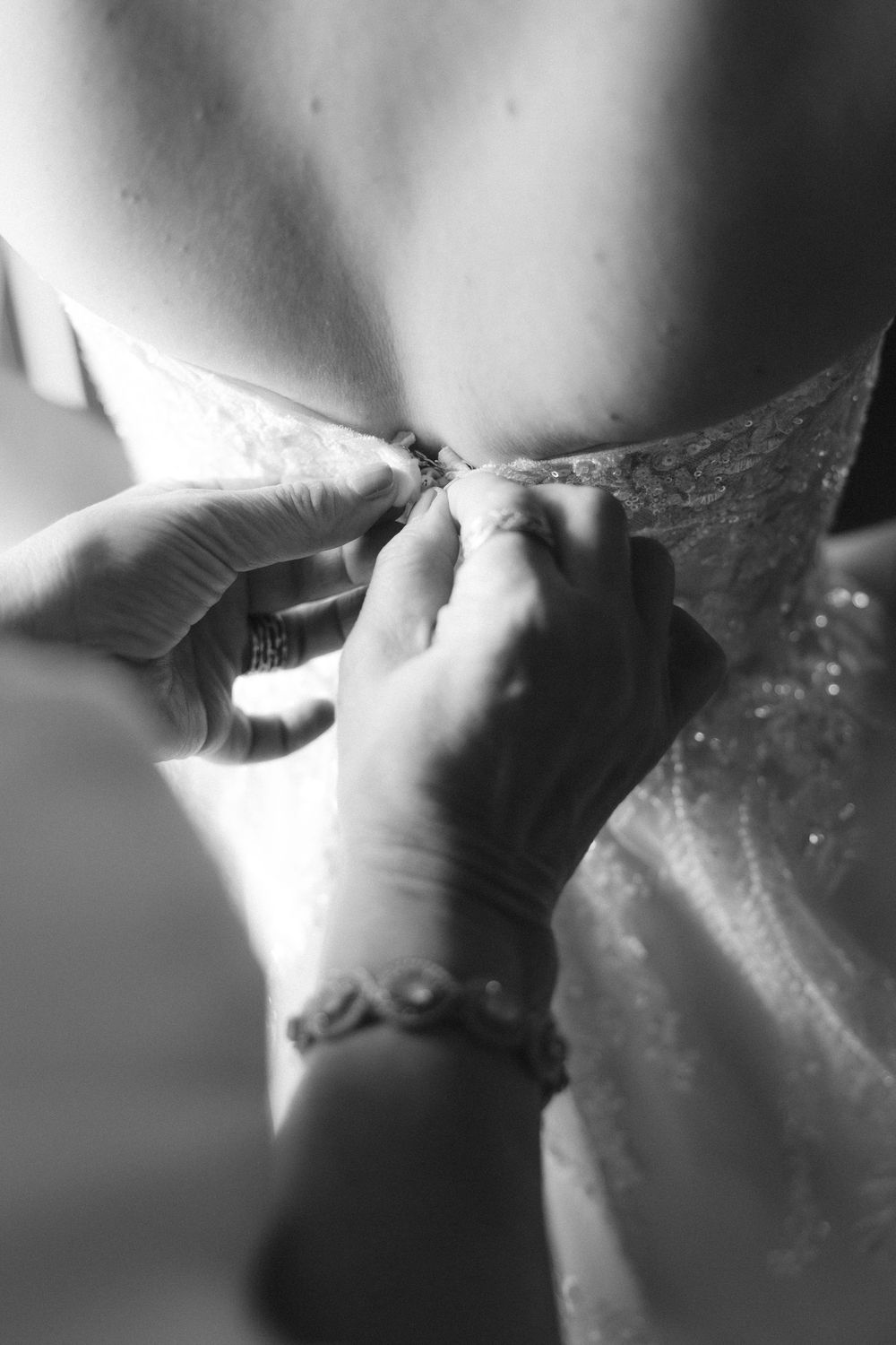 Close-up black and white shots of someone fastening jewelry around their neck.
