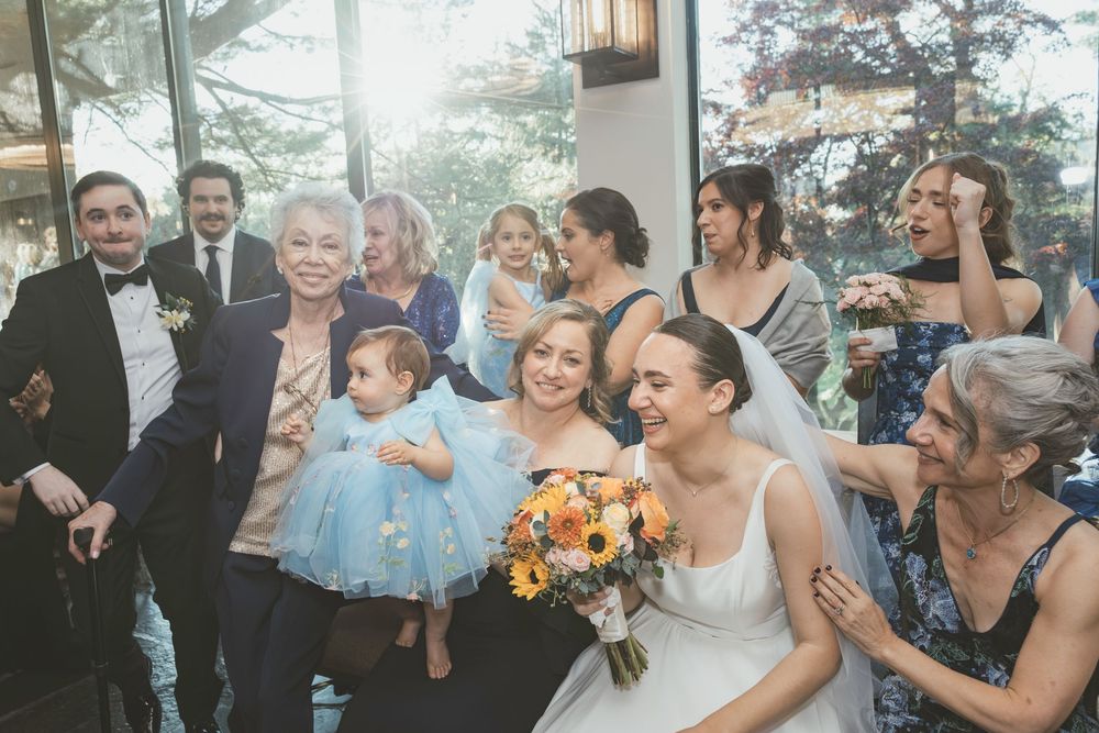 Wedding celebration scene in bright indoor venue with large windows and festive crowd.