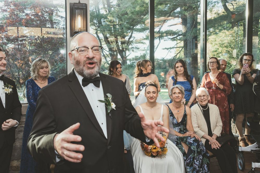Wedding reception gathering in modern venue with panoramic windows and natural lighting.