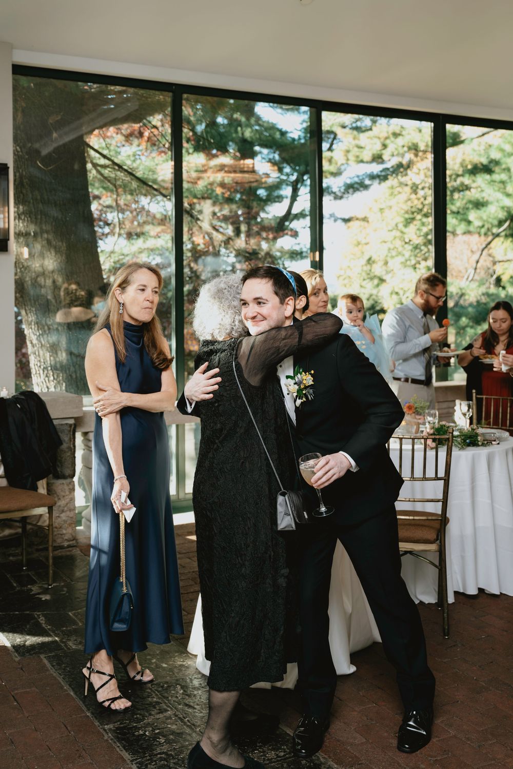 Wedding guests dancing and celebrating on a covered outdoor patio with forest views.