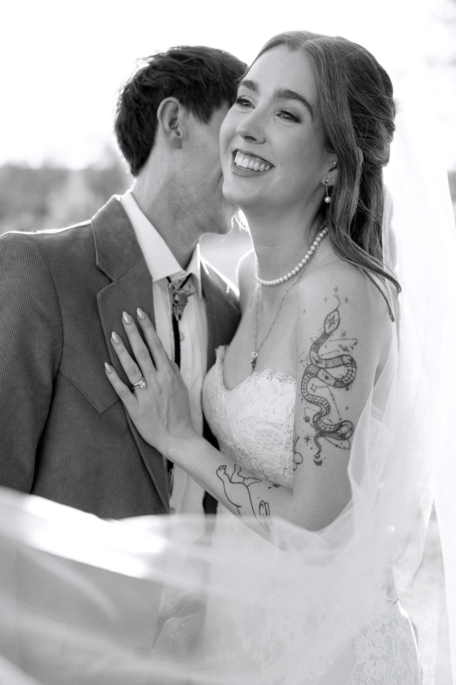 Black and white wedding photos show romantic moments between newlyweds sharing intimate kisses and laughter.