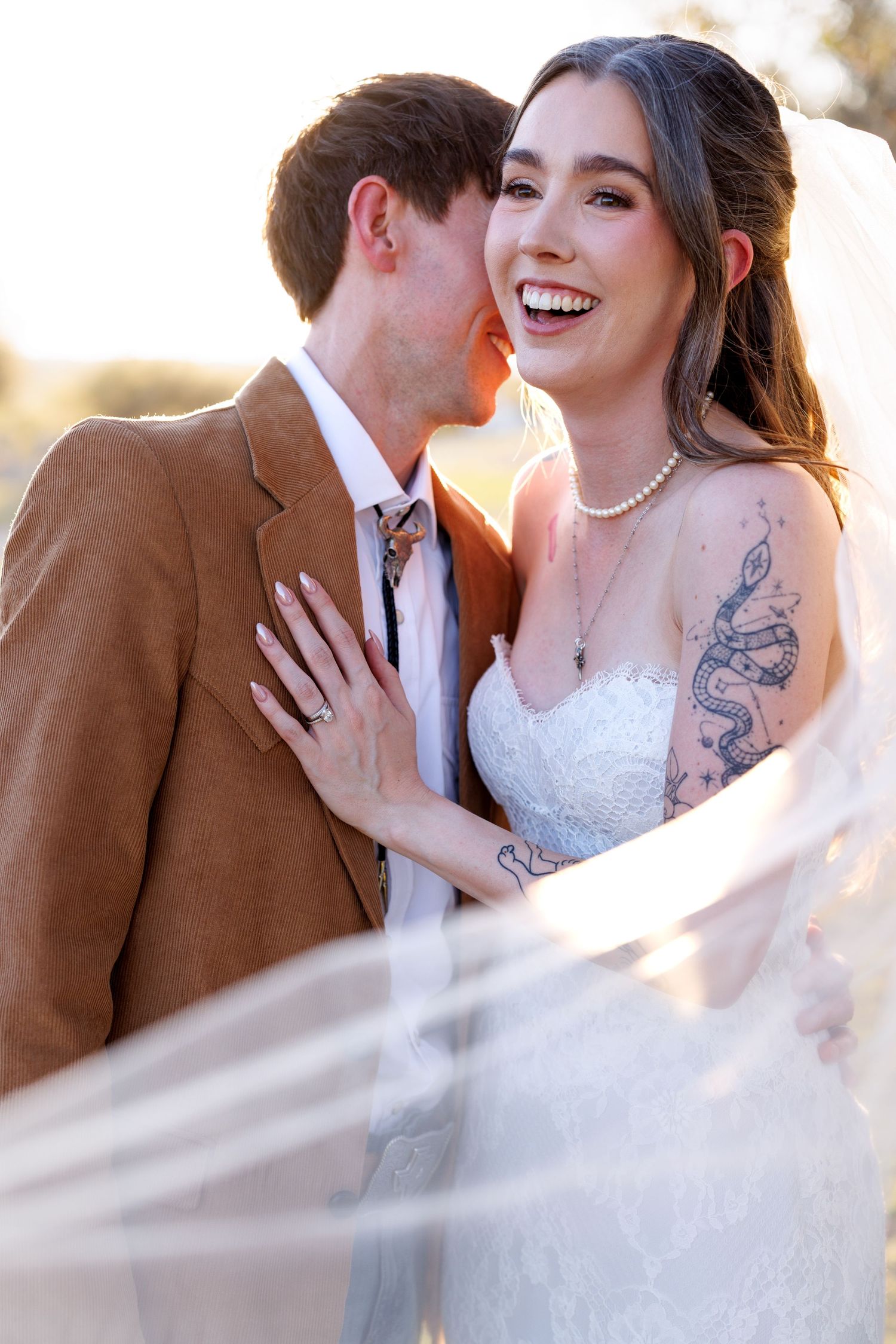 A romantic wedding moment captured in soft light showing the couple in an intimate pose with the bride wearing white lace.
