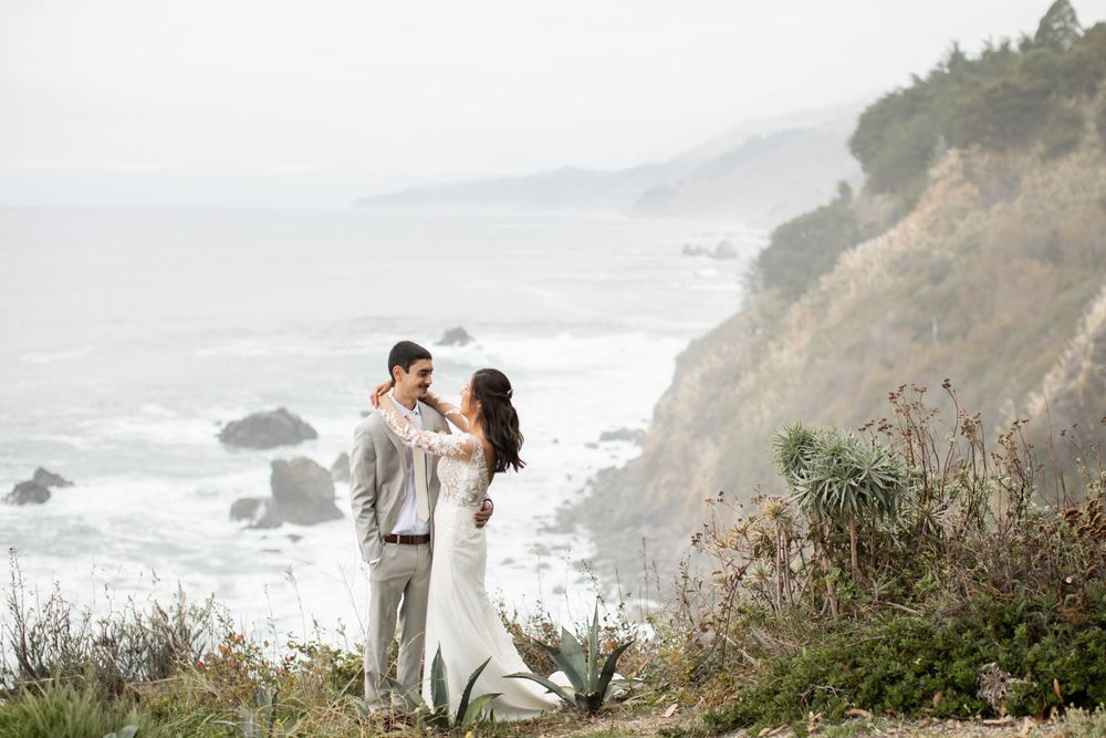 Couple shares romantic moment on scenic coastal cliffs overlooking Pacific Ocean during golden hour.