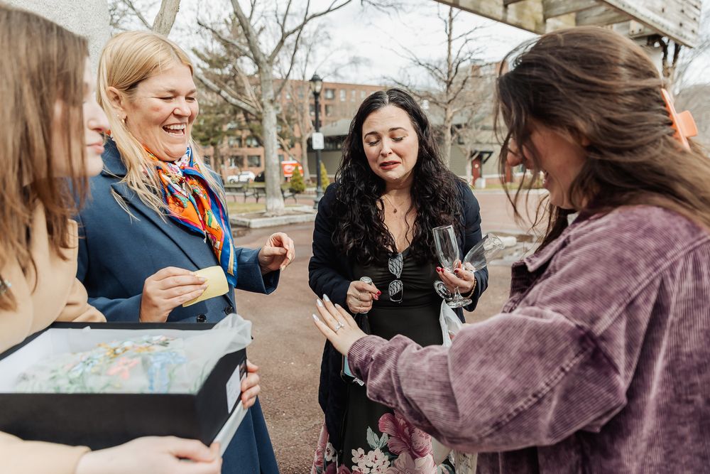 Three women laughing and socializing outdoors at a food and wine tasting event in an urban setting.