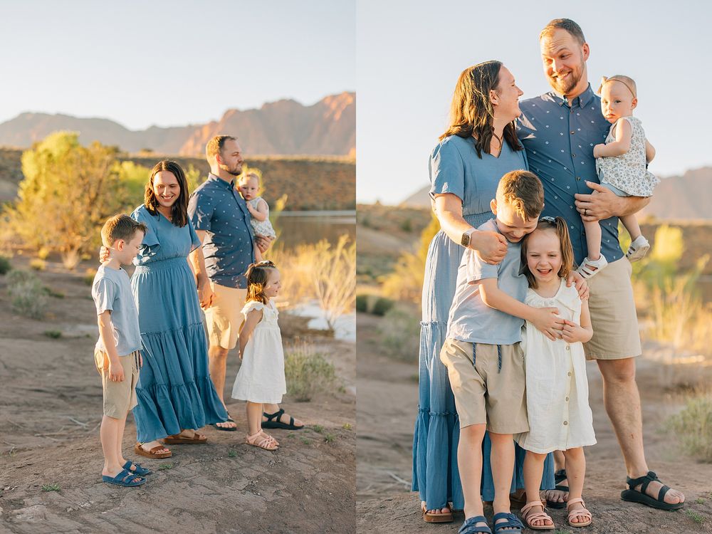 Family of five poses outdoors in coordinated blue and neutral outfits with red rock mountains glowing at sunset in Arizona.