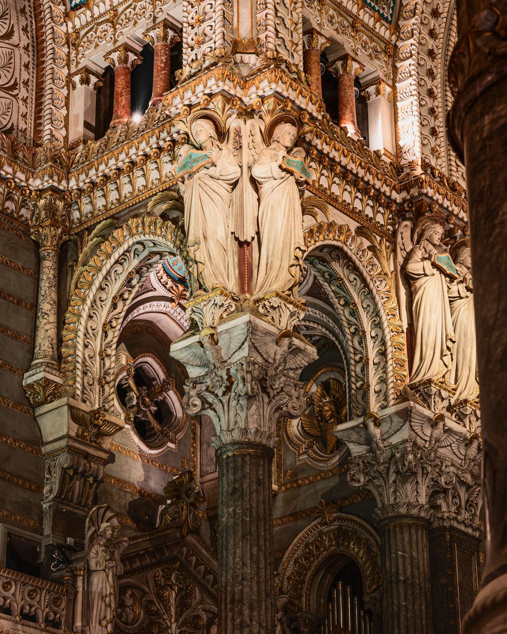 Ornate Gothic cathedral interior with gilded arches, intricate carvings, and white marble angel statues illuminated by warm light.