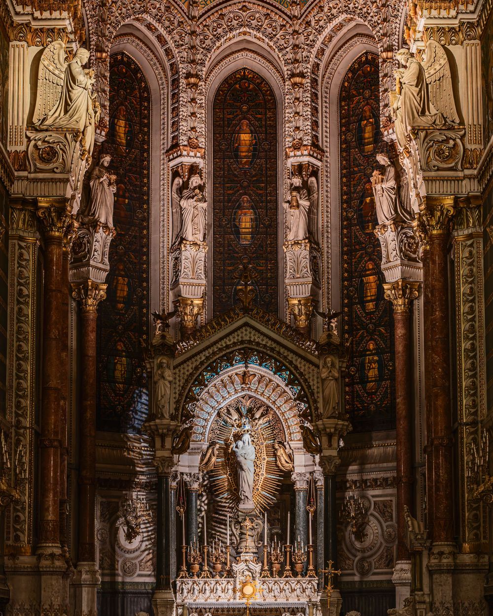 Ornate cathedral altar with golden arches, carved stone statues, and a central Virgin Mary figure in rich baroque style.