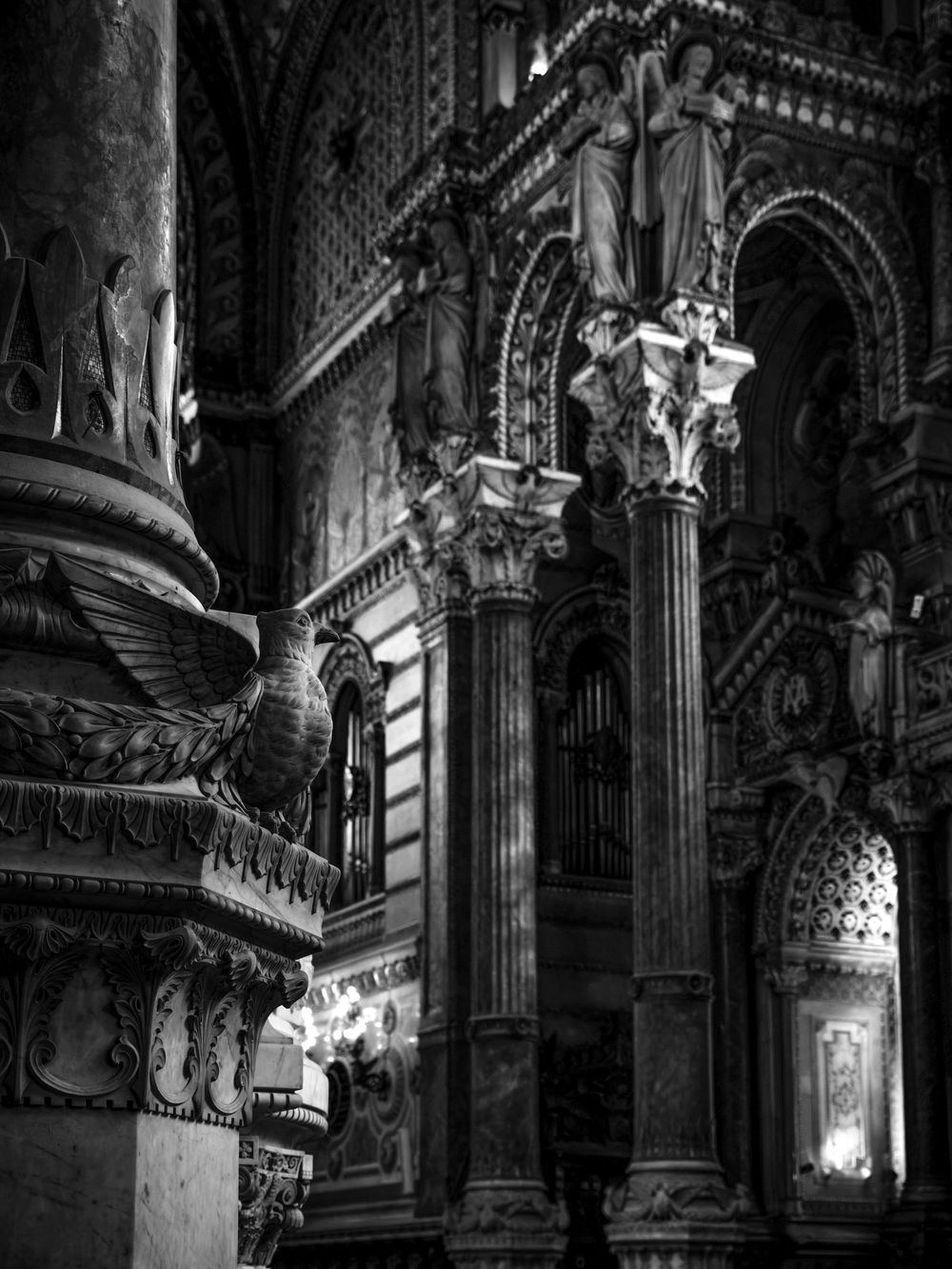 Black and white photo of ornate cathedral interior with detailed columns, sculptures, and arched doorways.