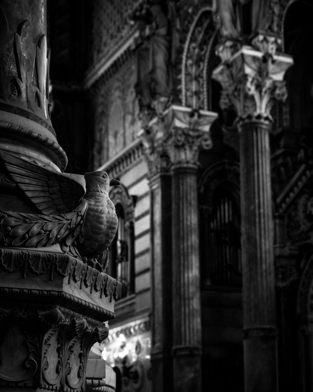 Black and white photo of ornate architectural details with eagle sculpture on decorative column in classical building.
