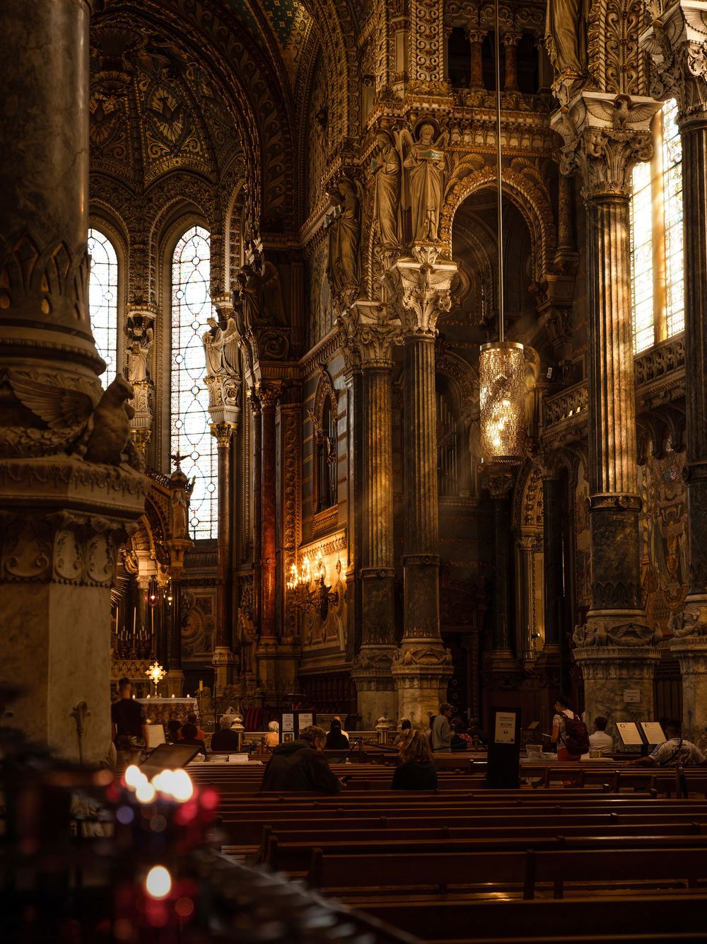 Ornate cathedral interior with golden columns, arched windows, and dramatic light rays illuminating the grand nave.