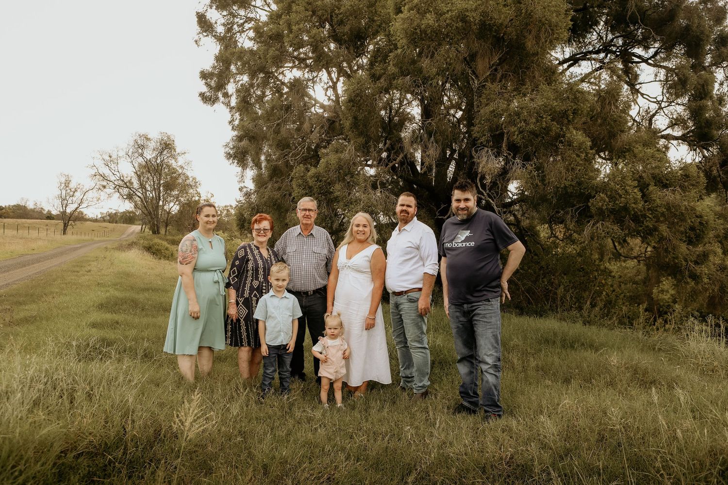 A group of people standing together on a grassy hillside in casual attire during an outdoor gathering.
