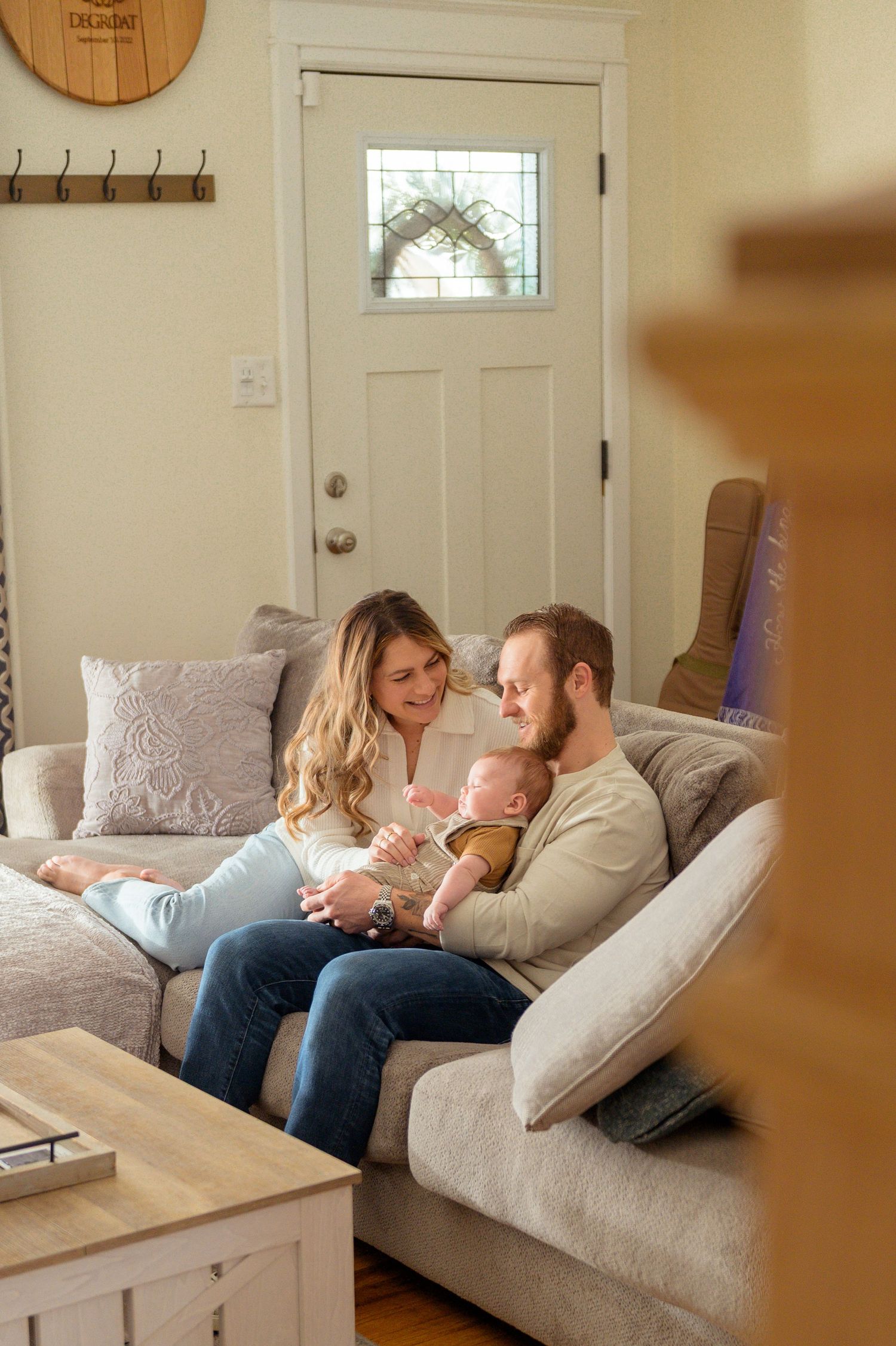 A family relaxes together on a cozy gray couch in their living room during a tender moment at home.