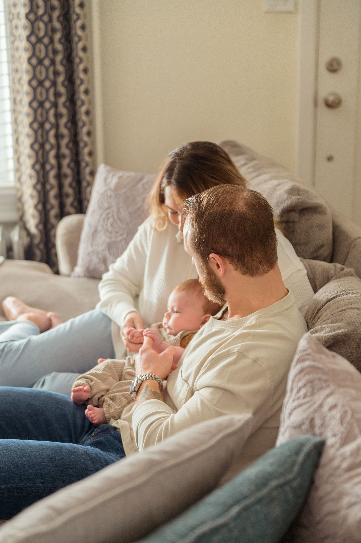 A series of four tender moments showing parent and baby cuddling together on a couch with soft lighting.