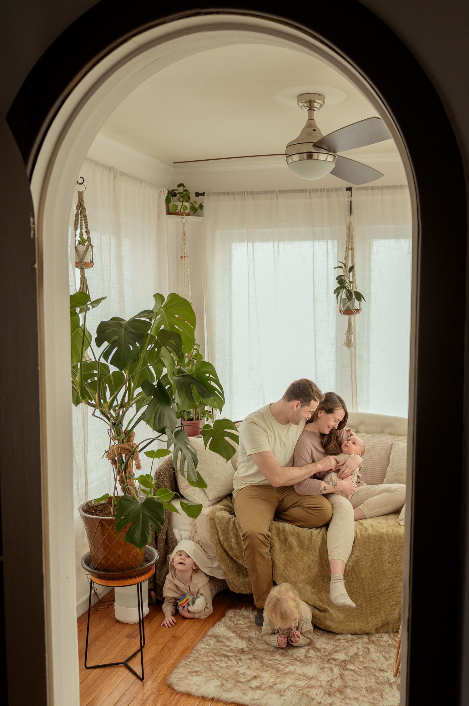 A sequence of four images showing a tender moment between parent and child on a beige couch in a sunlit room.