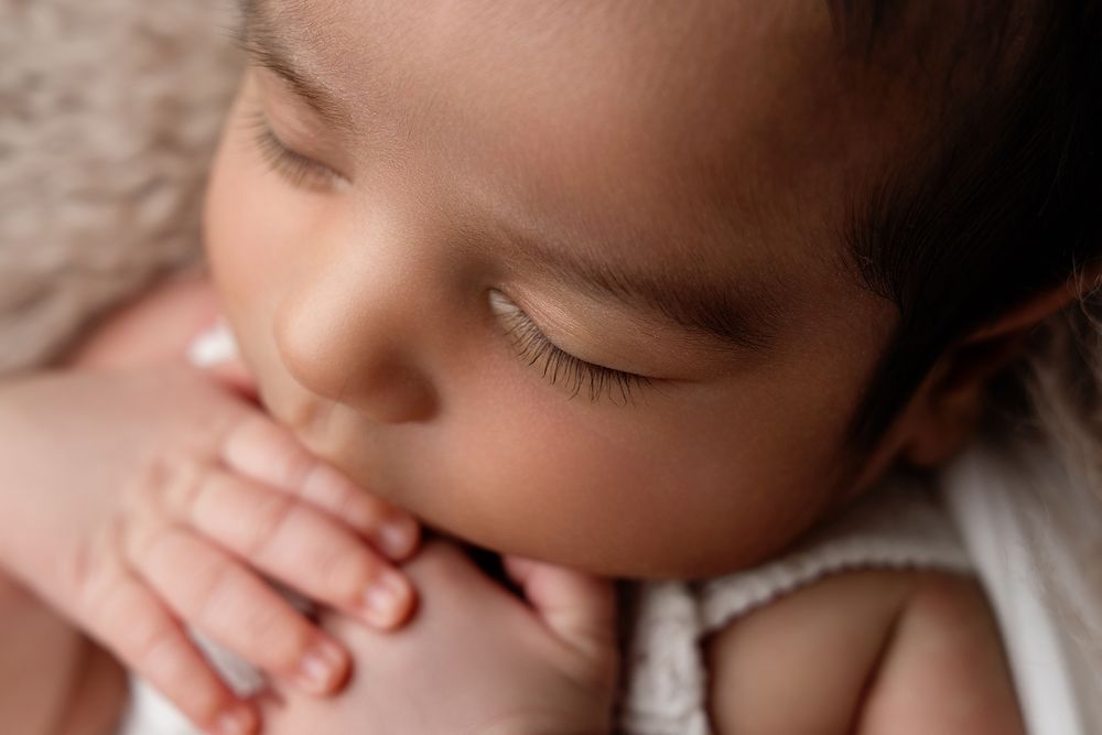 Adorable sleeping newborn baby with soft features rests peacefully in a natural light setting.