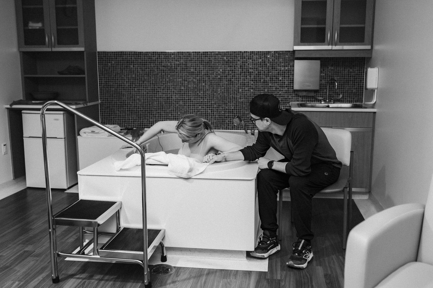 Black and white photo of two people studying together at a desk with a lamp in what appears to be a dorm room.