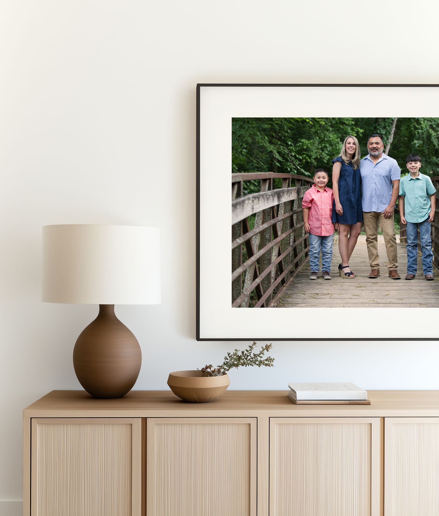 Modern living room wall features light wood cabinets with framed family portrait in Colleyville, TX