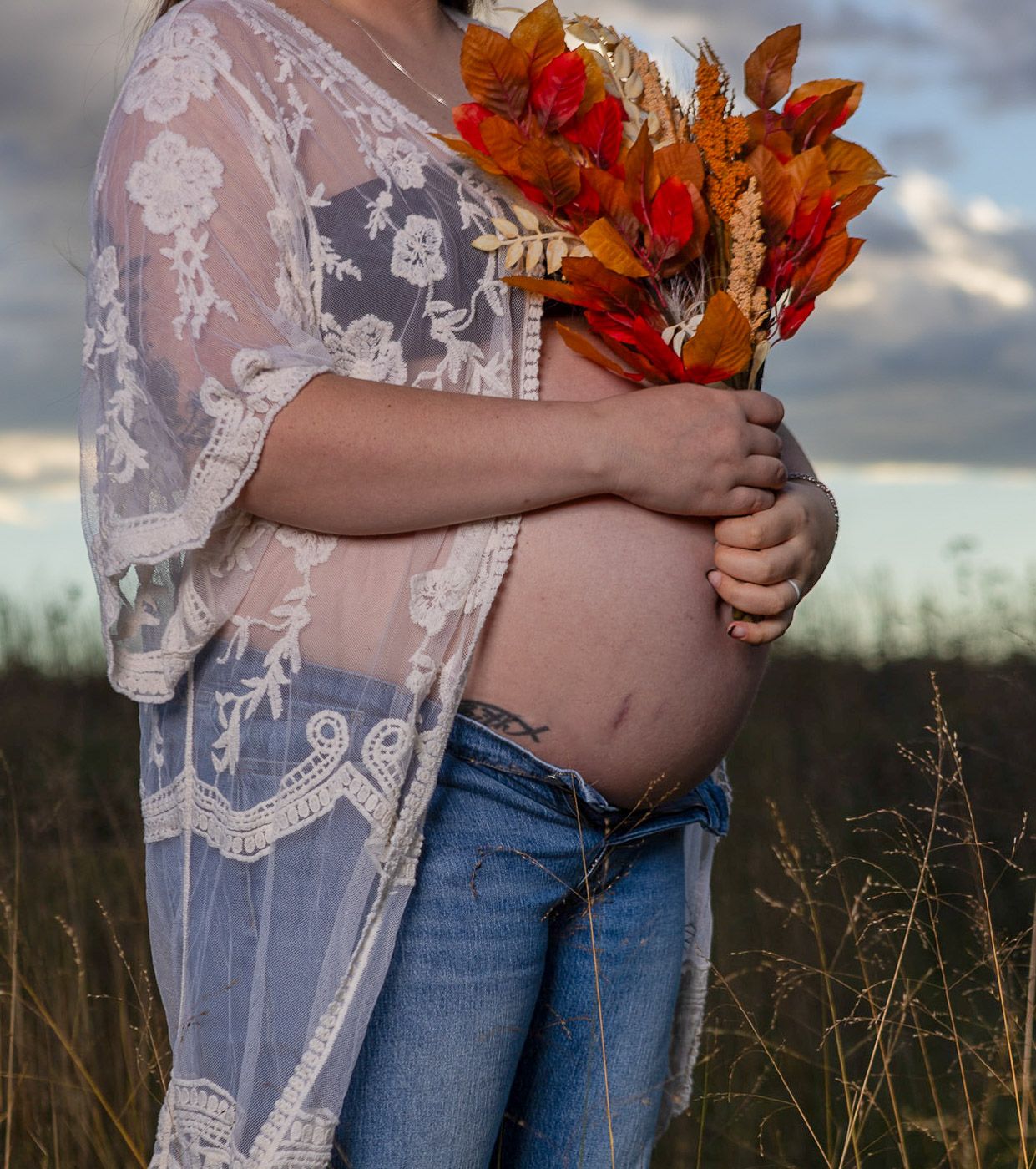pregnant belly in a field with mom holding autumn flowers