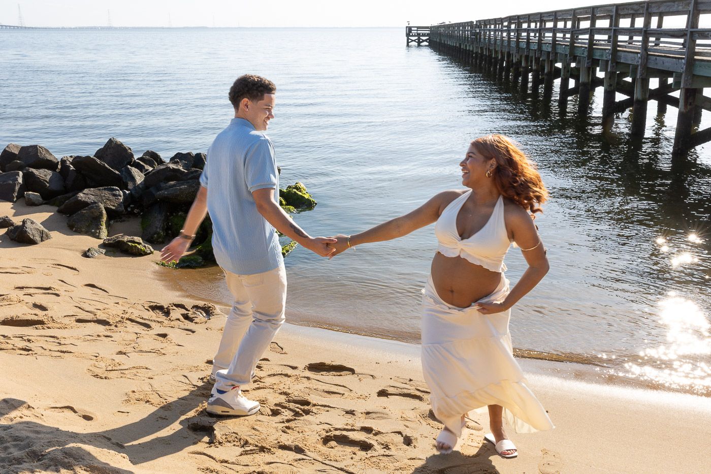 mom and dad spinning on the beach showing pregnant belly