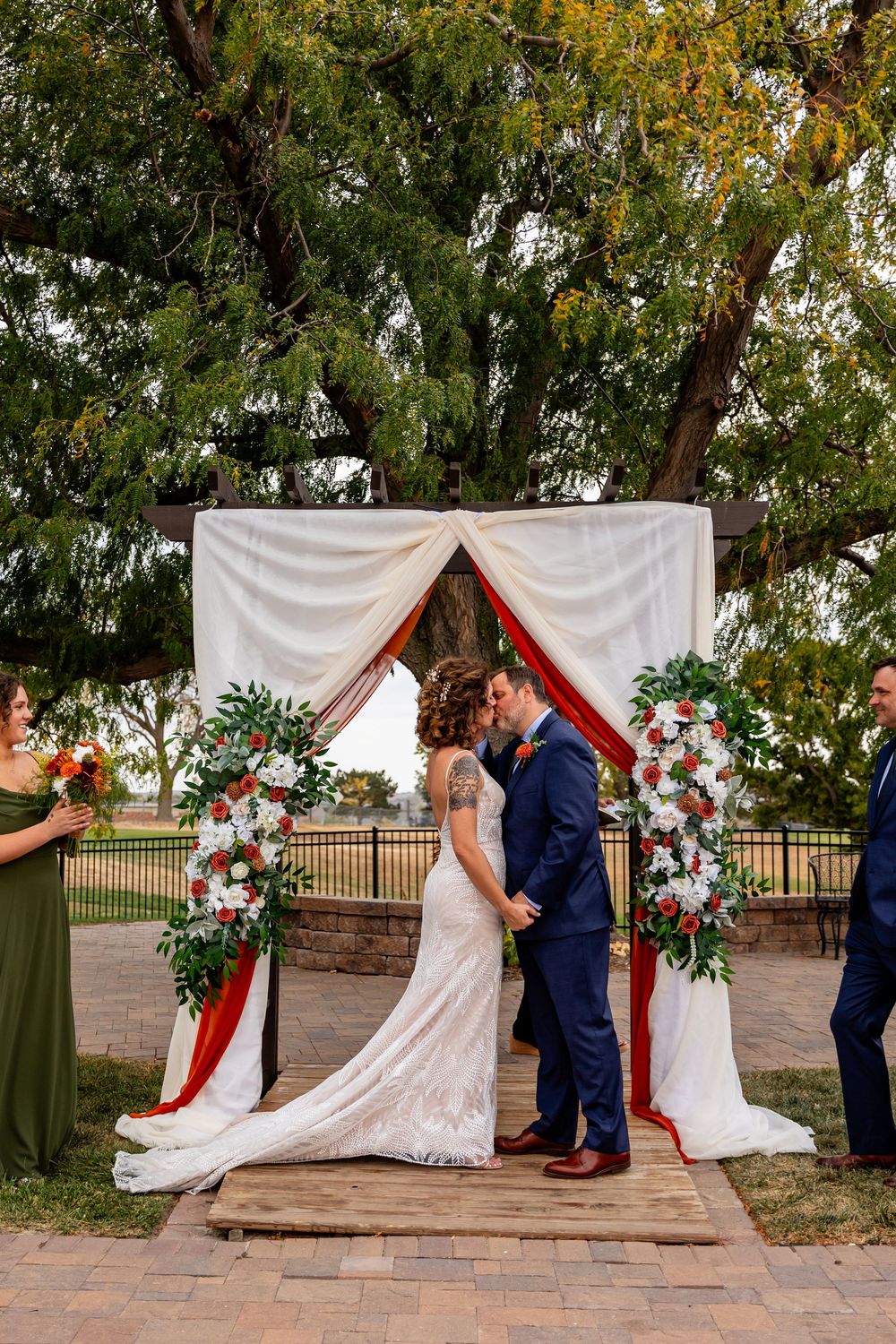 Bride and groom share a first kiss under a floral wedding arch at a Venue on the Ridge in Elkhorn NE