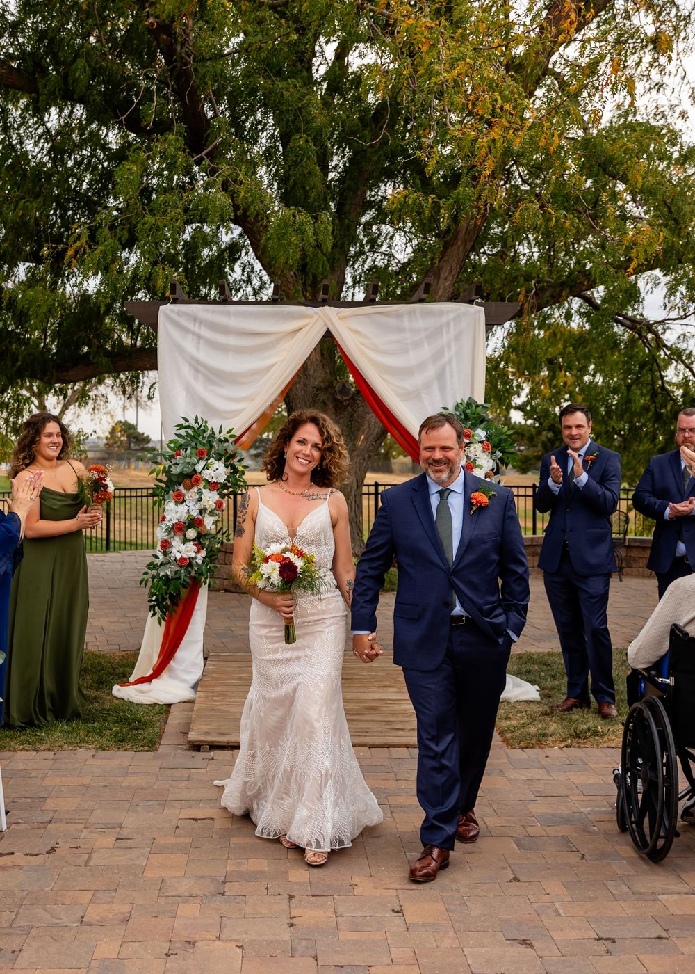 Bride and groom walk down the aisle hand in hand after outdoor wedding ceremony with guests applauding at a Venue on the Ridge in Elkhorn NE