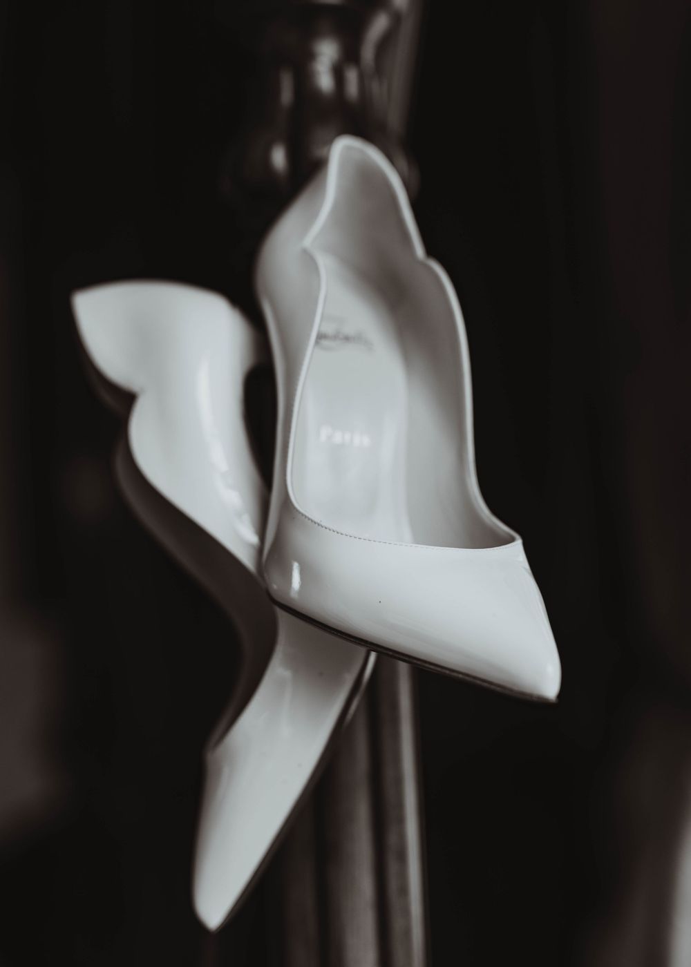 Elegant white pointed-toe bridal heels displayed in artistic black and white wedding photo.