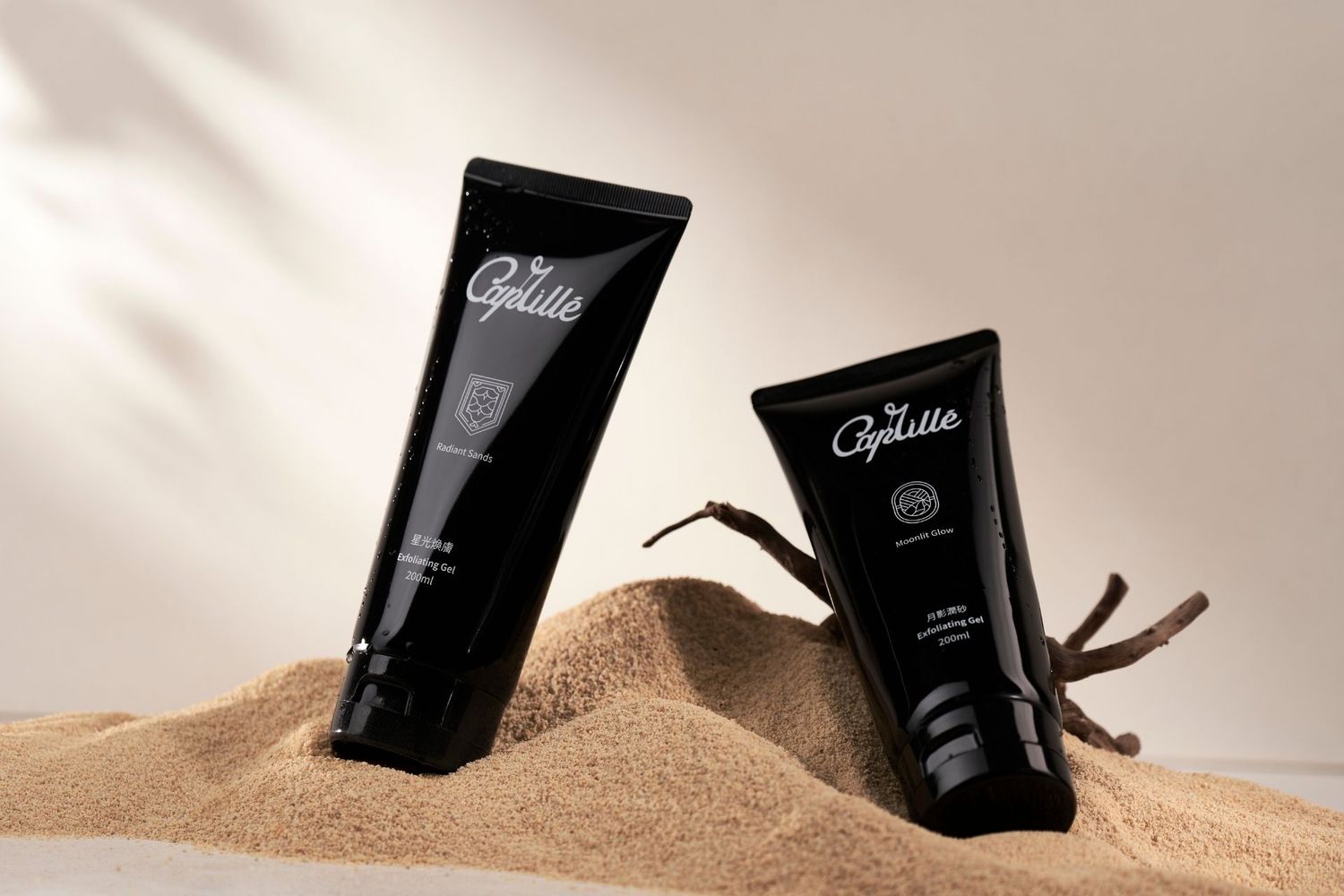 Black coffee packets arranged artistically in sand against beige background for product photography.