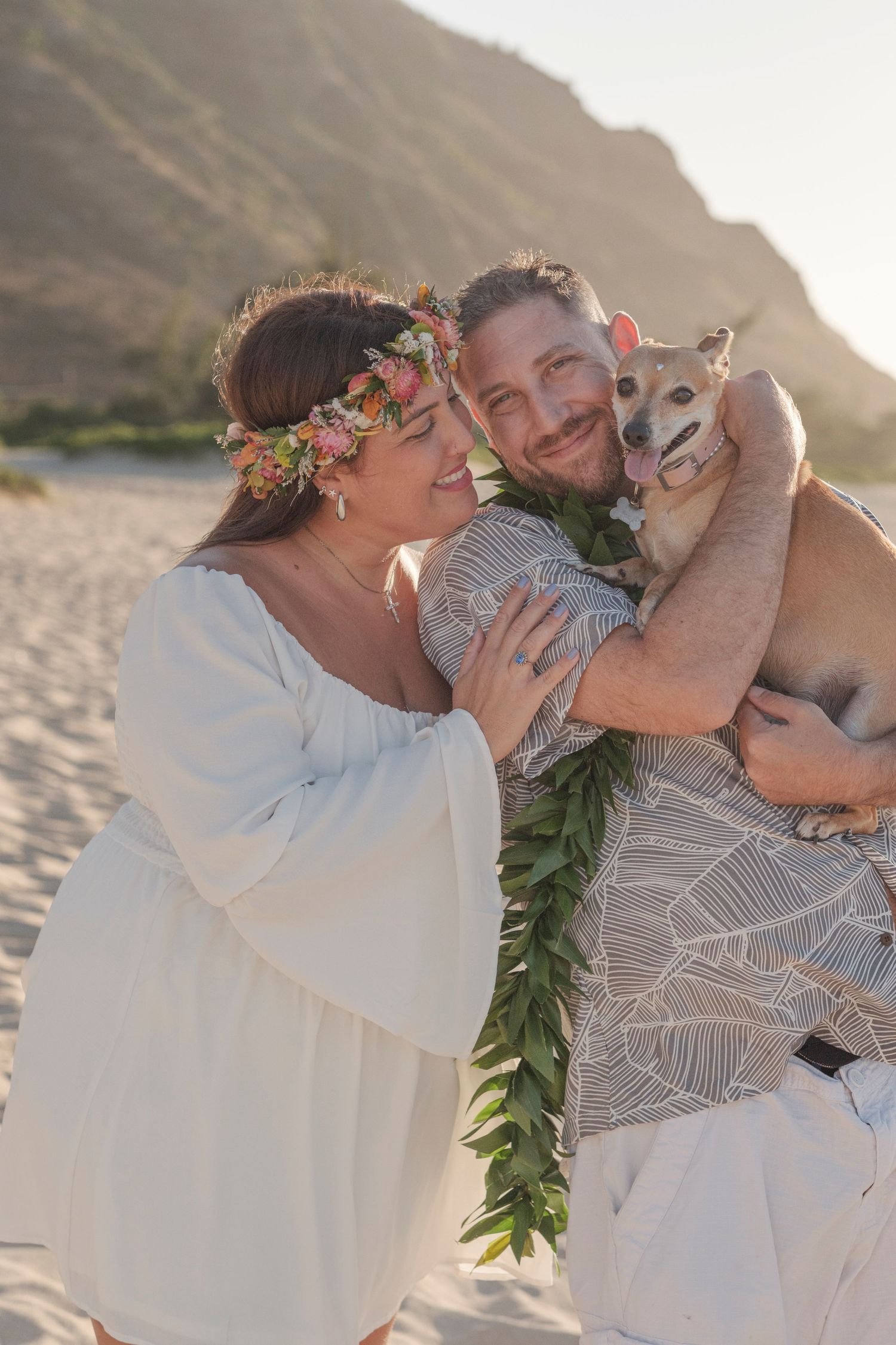Couple embracing on the beach with their dog during a North Shore Oahu couples photography session.