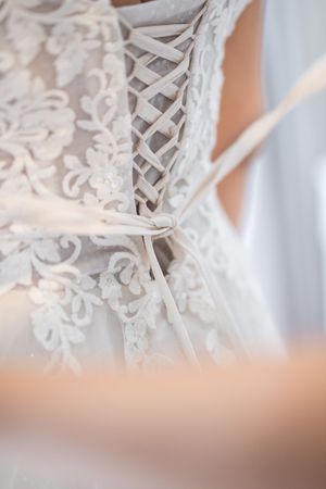 Close-up detail of delicate white lace with floral patterns and intricate embroidery on wedding dress fabric.