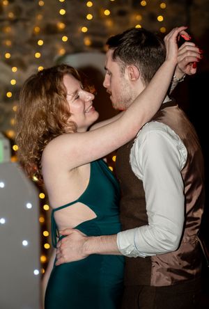 A romantic sequence of dance poses between two partners in front of twinkling lights at an evening celebration.