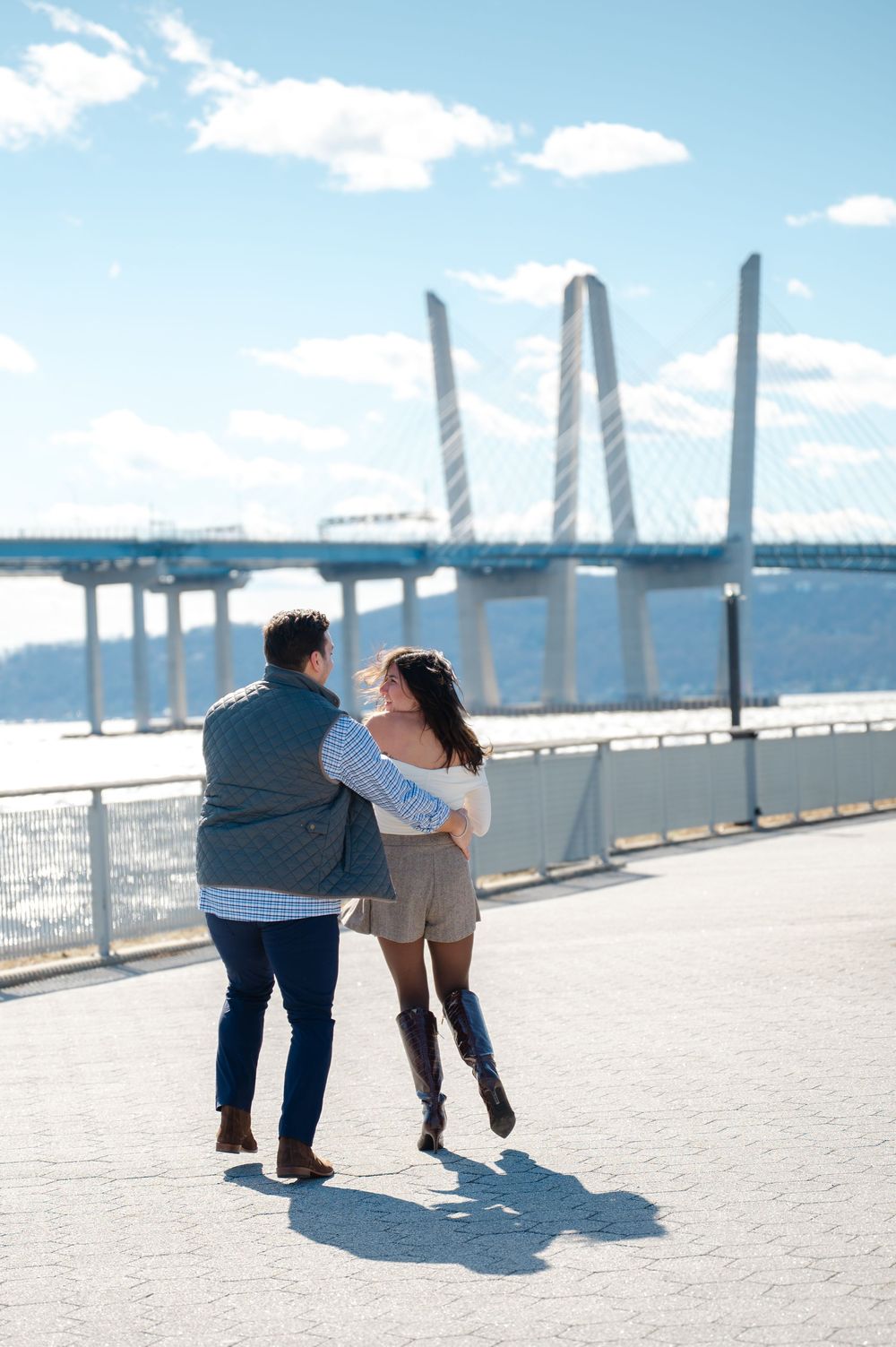 A couple shares a playful and romantic moment near the Hudson River during their engagement session in Tarrytown, NY (Westchester).