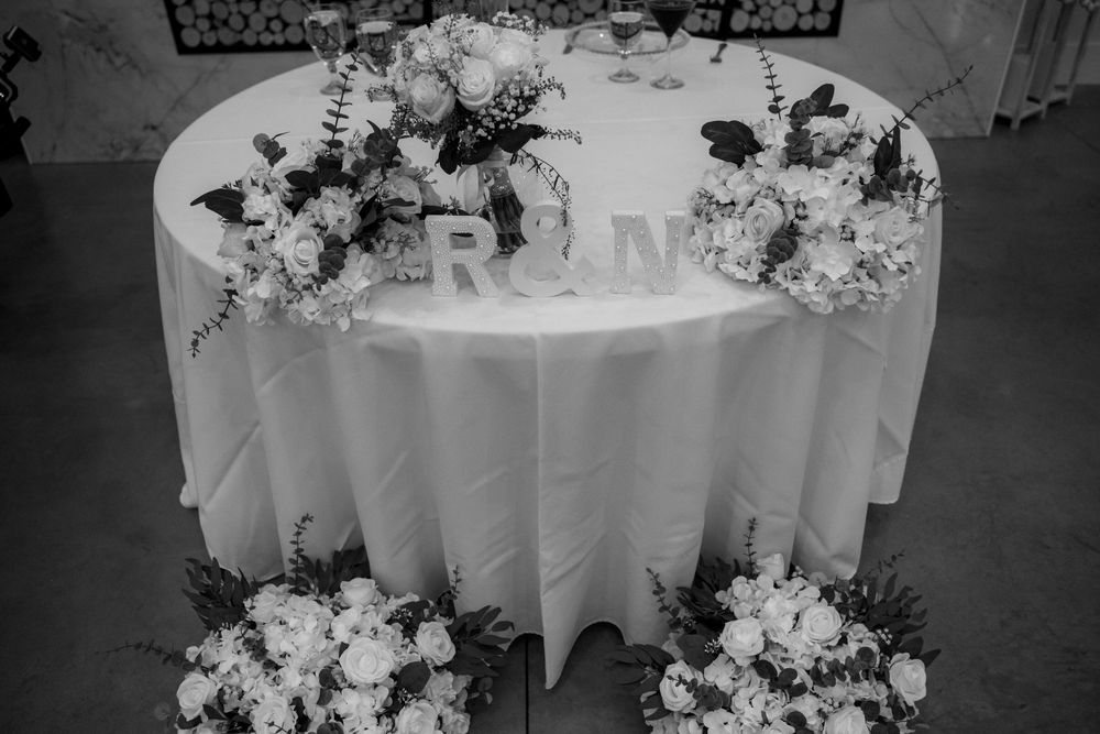 Black and white wedding sweetheart table with floral arrangements and R&N monogram letters centerpiece.