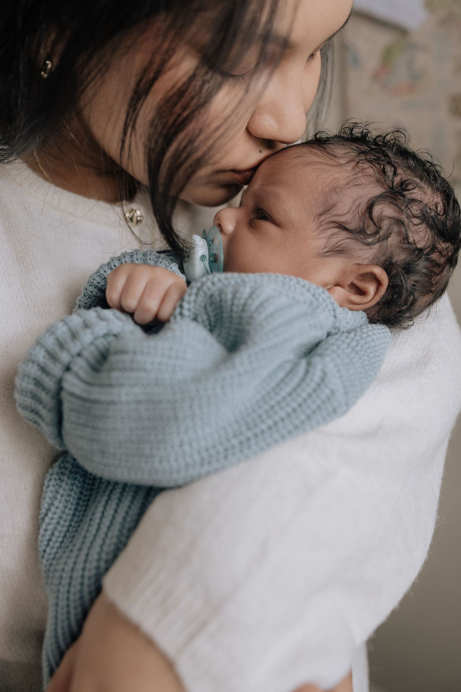 A tender moment captured in soft tones as parent and baby share loving cuddles in a cozy sweater.