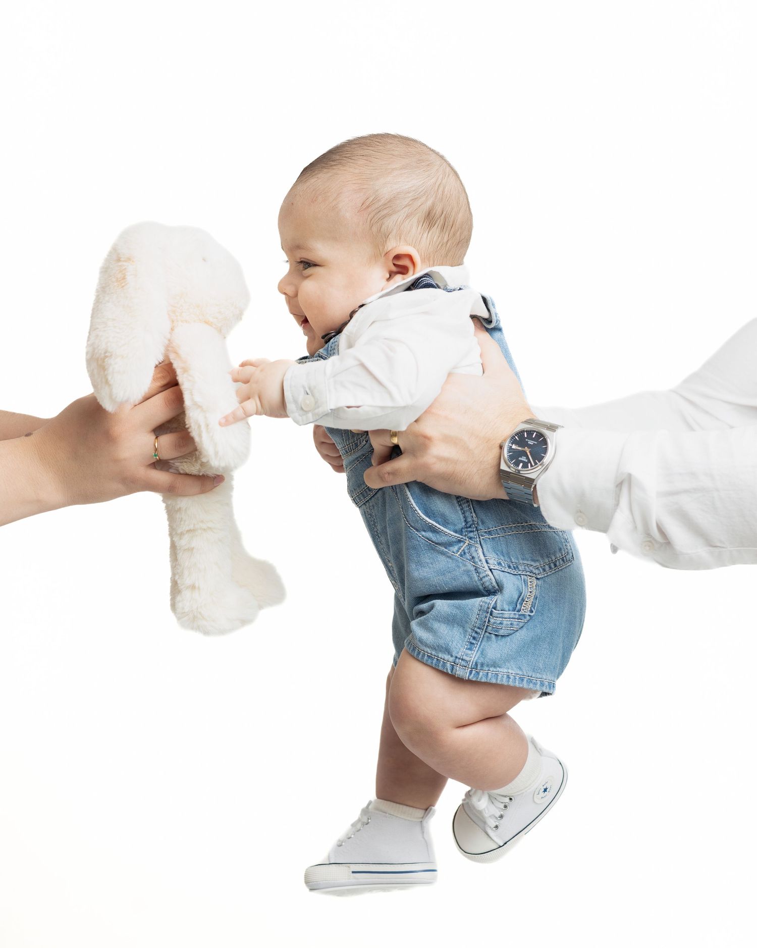 A baby in denim overalls crawls across a white background in a sequence of four progressive movement poses.