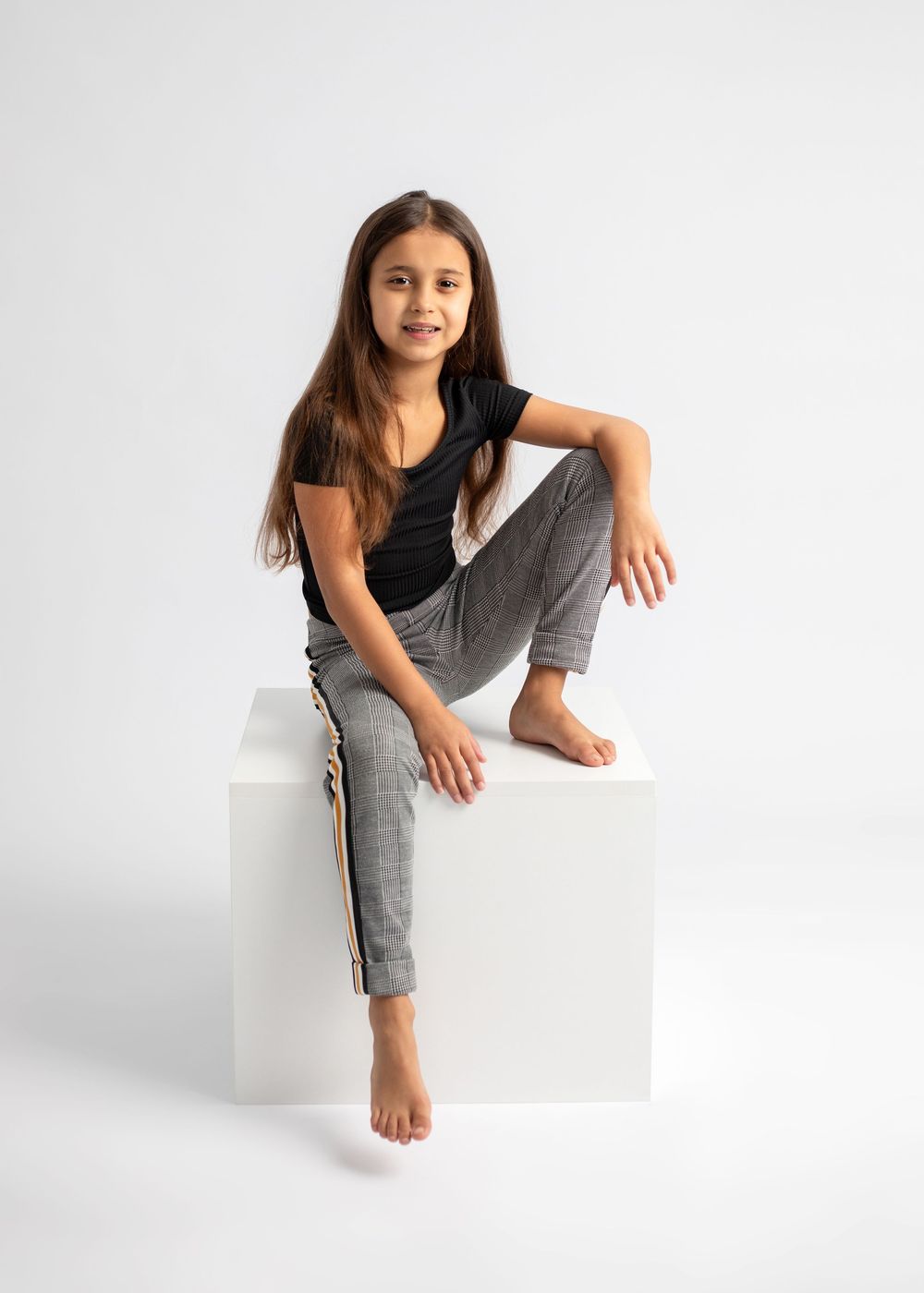 A person in casual gray attire sits on a white cube in three different relaxed poses against a light background.