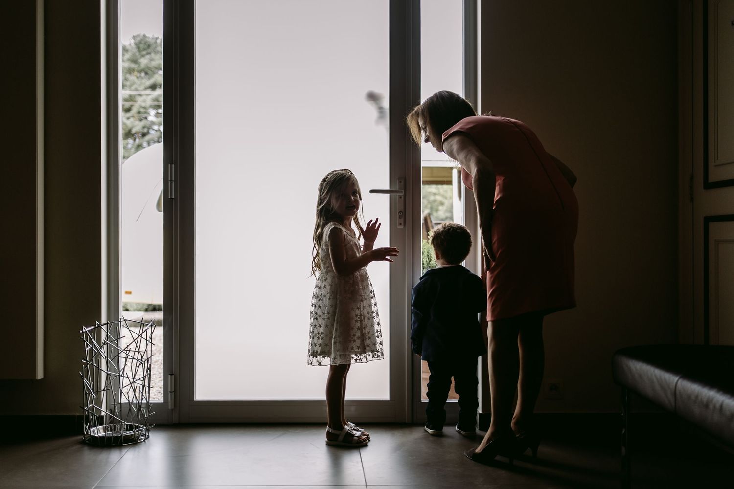 Silhouetted figures against bright windows creating dramatic wedding day composition.