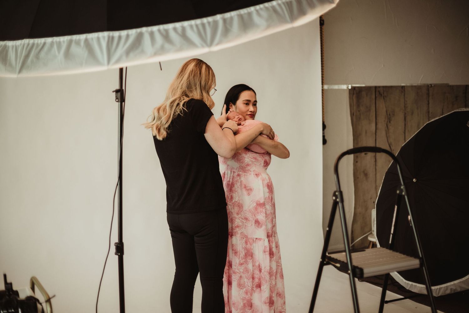Behind-the-scenes photo shoot with photographer adjusting client's pose in studio setting.