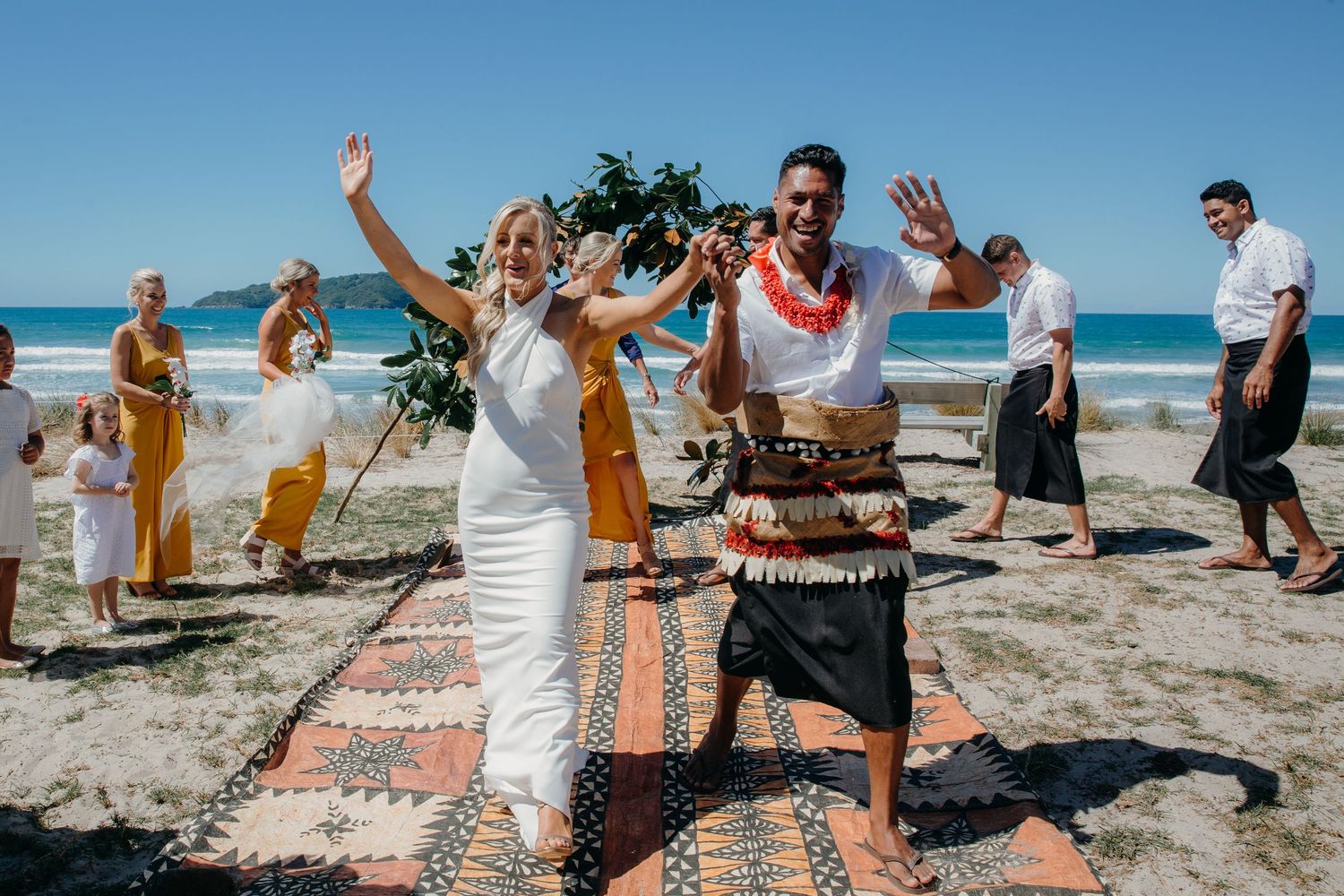 Auckland wedding photographer capturing a European bride and Pasifika groom walking up the aisle at their outdoor Coromandel wedding.