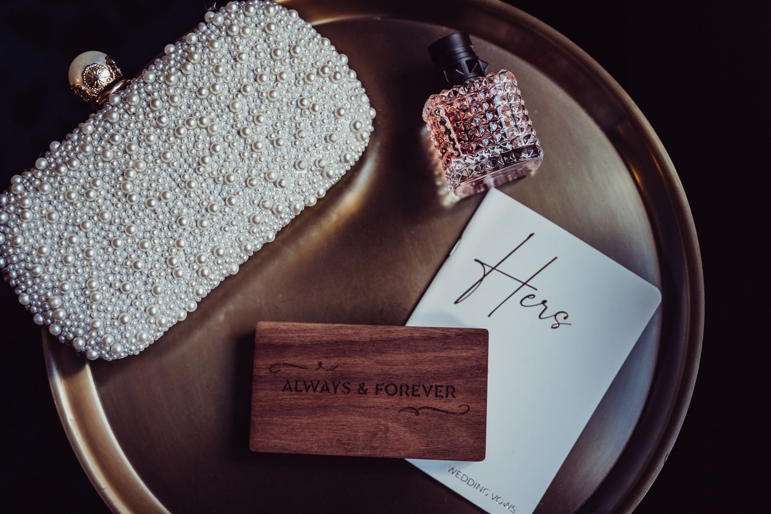 A wooden ring box and handwritten note sit on a dark wooden tray with delicate lace details.