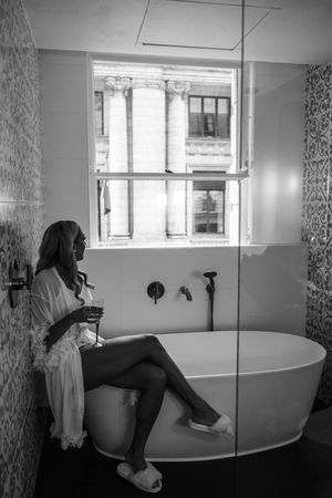 A series of four black and white photographs showing a freestanding bathtub in a modern bathroom with natural light.