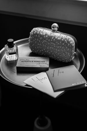 A sparkly silver clutch purse with rhinestones sits on a dark surface next to a handwritten note.