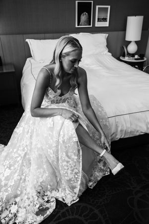 Black and white photo series showing close-up details of a white lace wedding dress being put on.