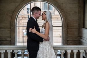 A couple shares romantic wedding photos in a stone archway corridor, showcasing intimate moments in formal attire.