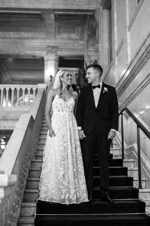 Black and white wedding photos show a couple in formal attire posing together on elegant stone stairs.
