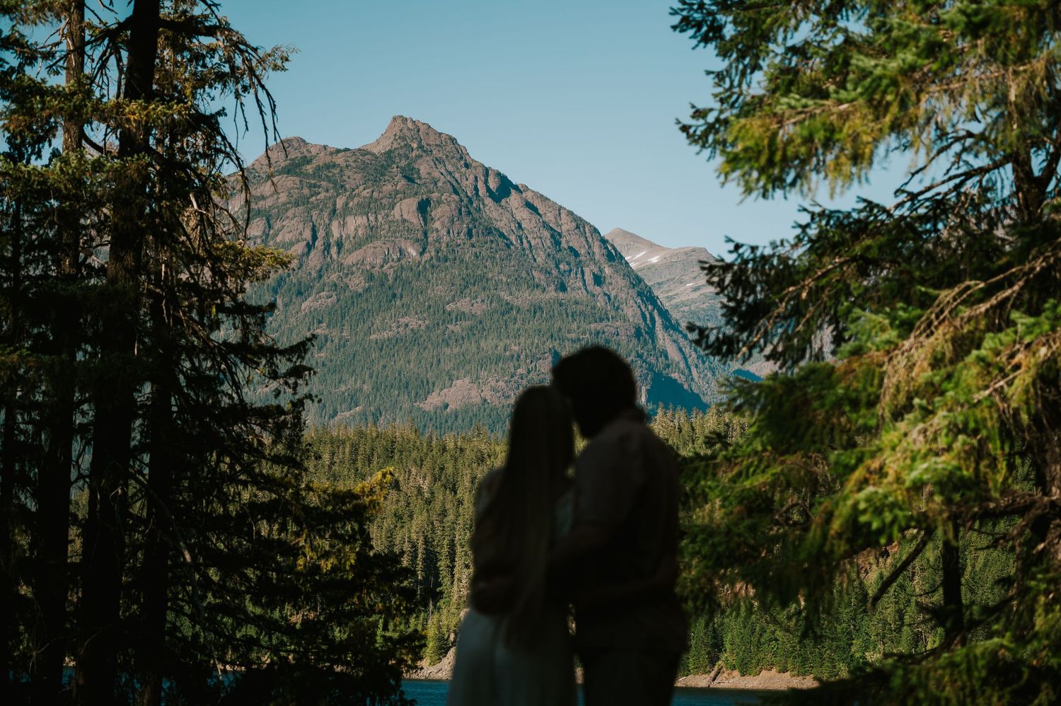 Couple adventure photoshoot at Myra Falls on Vancouver island taken by professional photographer of couple by mountain and Buttle lake